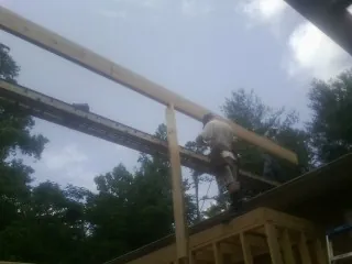 Carpenter setting a ridge beam over a new addition frame — Ice Dam Removal by Roofing Brothers in Lewis