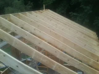 New roof rafters set over an addition before sheathing in Lewis