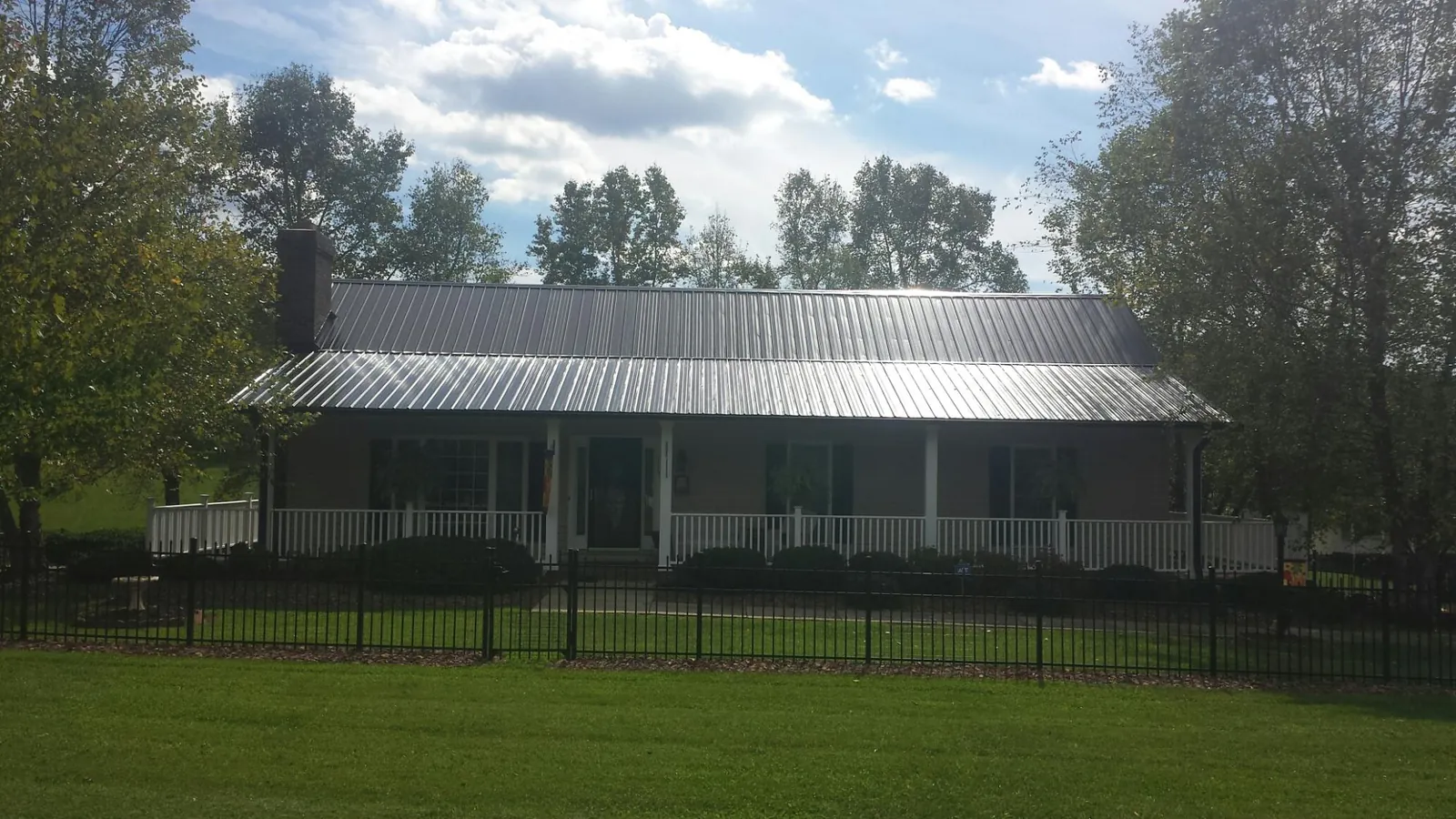 Gray metal roof on a brick ranch with a full width front porch — Gutter Guard Installation work by our crew in Lewis